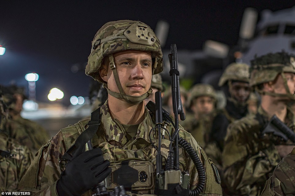 US troops stand on runway at Riga International Airport when they arrive in Latvia on Thursday