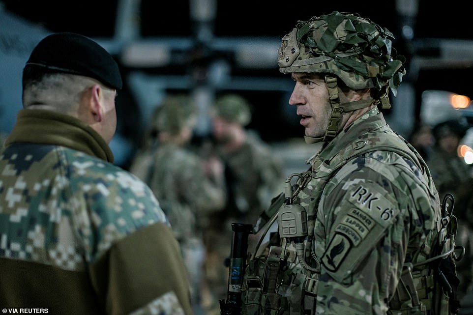 US troops stand on runway at Riga International Airport when they arrive in Latvia on Thursday