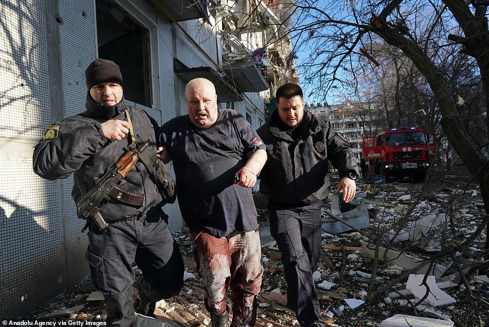 Ukrainian security forces escort a wounded man after an air strike on a residential complex in Chukhuyev, Kharkov