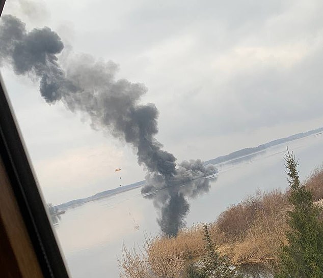 An image taken near Kiev shows the remains of a downed Russian attacking helicopter with a soldier parachuting from it (left of the frame)