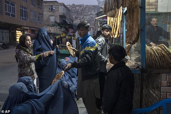 A man distributes bread to Afghan women in front of a bakery in Kabul, Afghanistan, in December as prices rise in the country after the Taliban took power