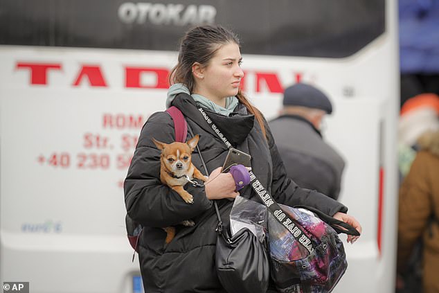 A Ukrainian refugee - among 200,000 who were forced to flee the country after the Russian invasion - carries a small dog under his arm when he arrives in Siret, Romania