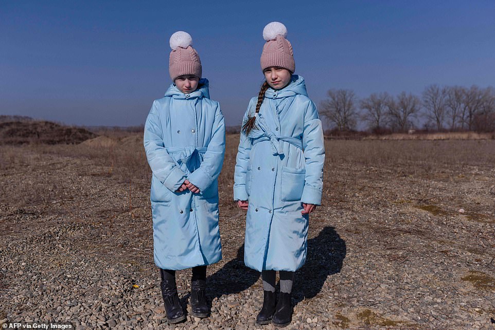 Anna Zadorozhnyak (right), 10, and Olga Zadorozhnyak, 8, from the Ukrainian city of Chernivtsi, pose for a photograph after crossing the Ukrainian-Romanian border in Siret, northern Romania, on March 19.