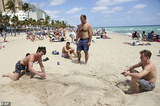 Spring break usually falls in the last two weeks of March, when most schools and colleges have a week off.  Above, Colorado School of Mines (center) students Carter Noere, 22, Weston Hunt, 22, and Jack Damenti, 22, watch Anderson Salisbury, 22, sculpt a large dolphin out of sand on a Fort Lauderdale beach on Tuesday.