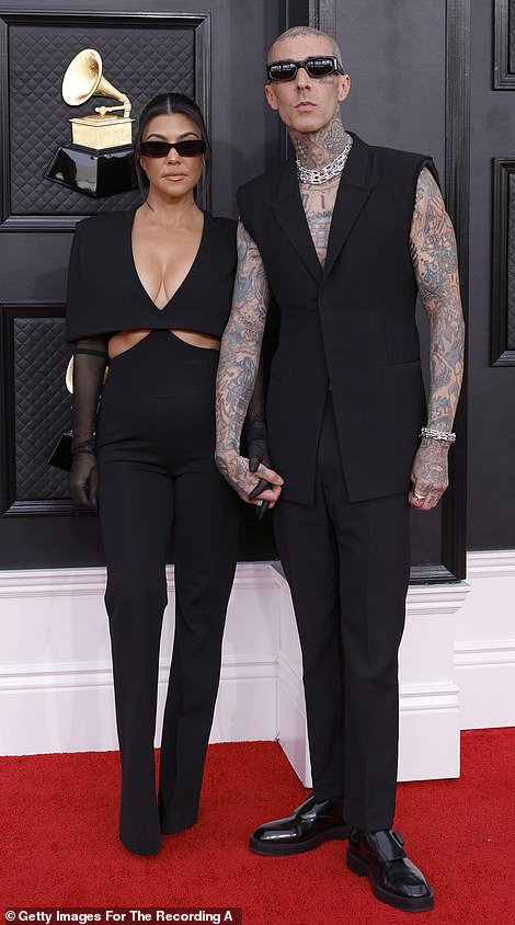 Revealing: Kourtney, who arrived on the red carpet wearing slim black sunglasses to match Travis, wore a statement top with a busty, plunging neckline and boxy shoulders that draped over her arms