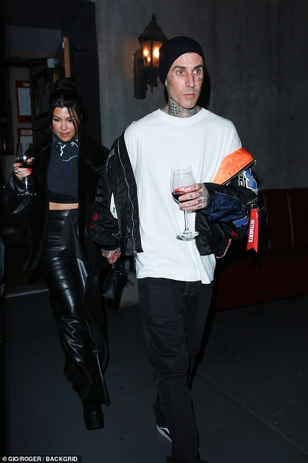 Kourtney Kardashian and Beau Travis Barker carry tall glasses of