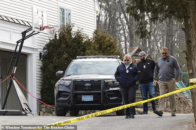 Police in the driveway of the house.  A basketball hoop can be seen next to the garage