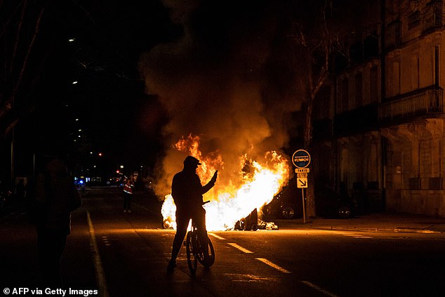 A protester takes photos of a fire during a demonstration in Dijon on Monday night