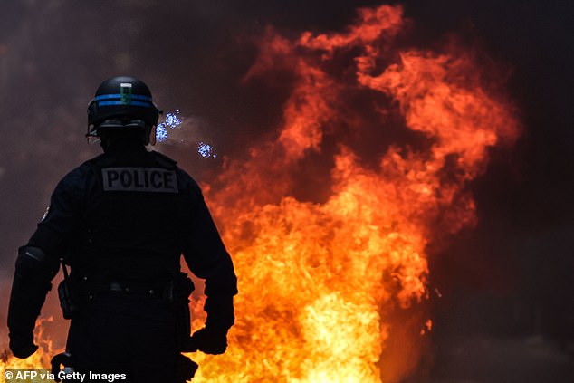 A rioted French police officer watches fire during a demonstration against the plans in Bordeaux, southwest France, on Saturday