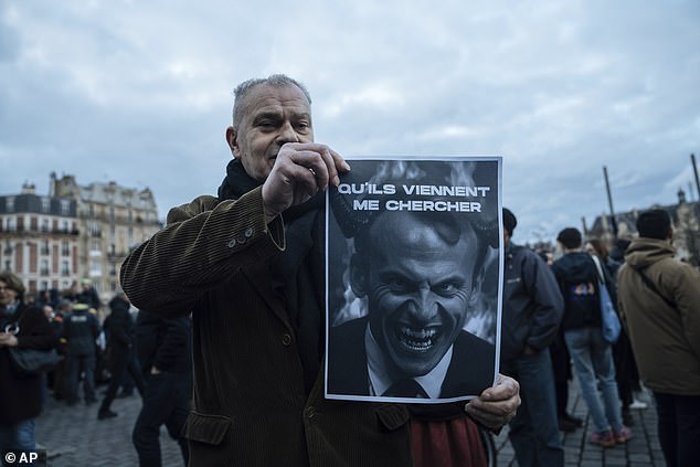 A protester holds a placard with Macron's face reading 