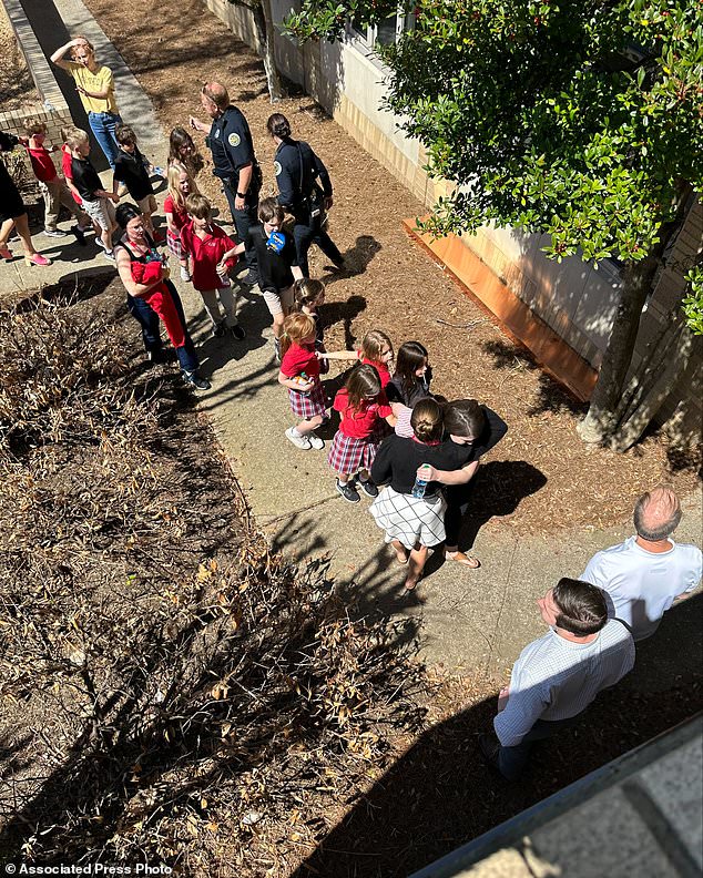 Children from Covenant School, a private Christian school in Nashville, hold hands as they are taken to a reunion site at Woodmont Baptist Church after the shooting