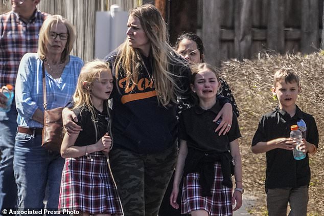 Children and a woman, all visibly shaken, are seen at the school after the shooting