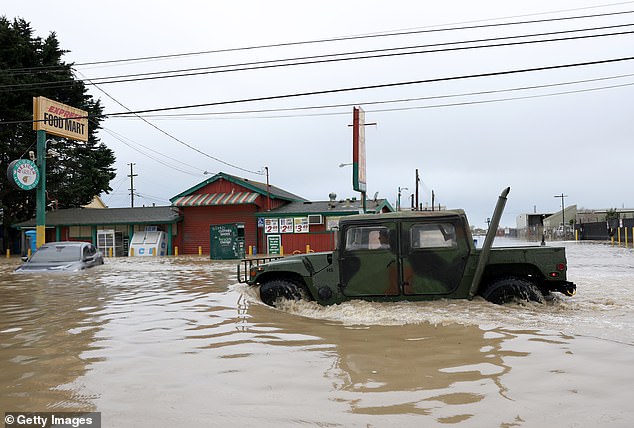 A series of severe storms prompted California to push back the tax return deadline for nearly all residents to October, complicating budget forecasting.  Pictured: A military vehicle drives through flood waters March 14 in Pajaro, California