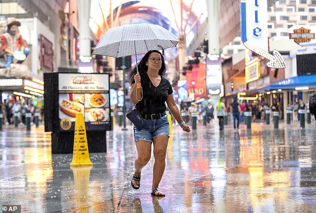 A woman runs through the rain on Fremont Street in downtown Las Vegas on Saturday