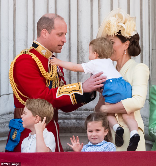 Prince Louis reaches out to his father Prince William as Princess Charlotte waves to crowds during Trooping The Color in 2019