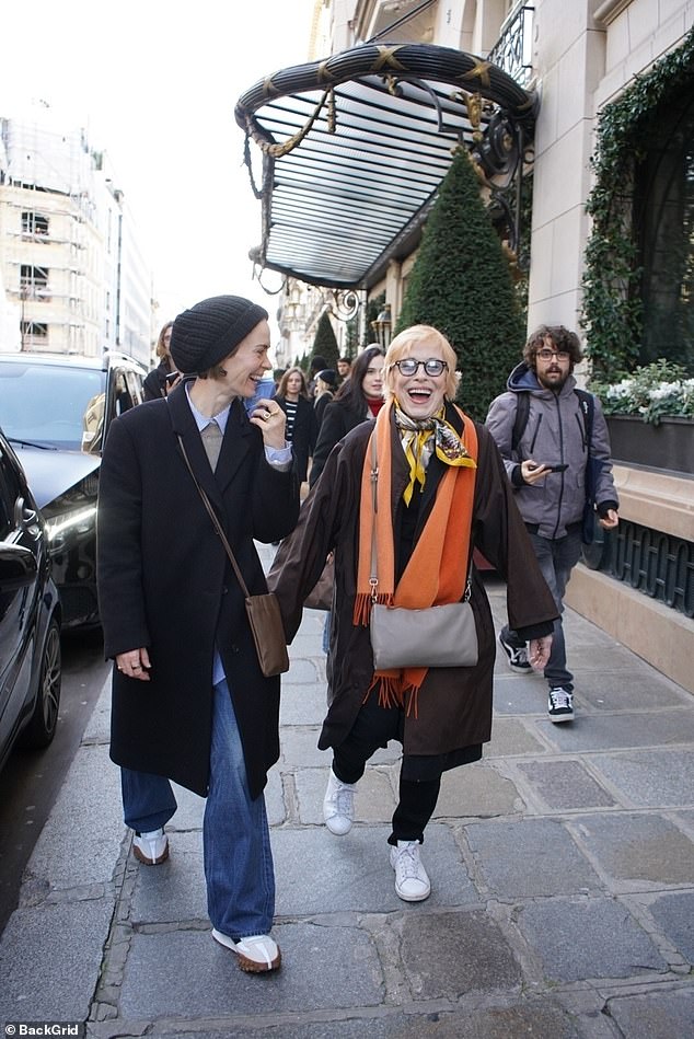 Meanwhile, Holland also wrapped herself in a long coat and a bright orange scarf, complementing it with a second yellow silk scarf